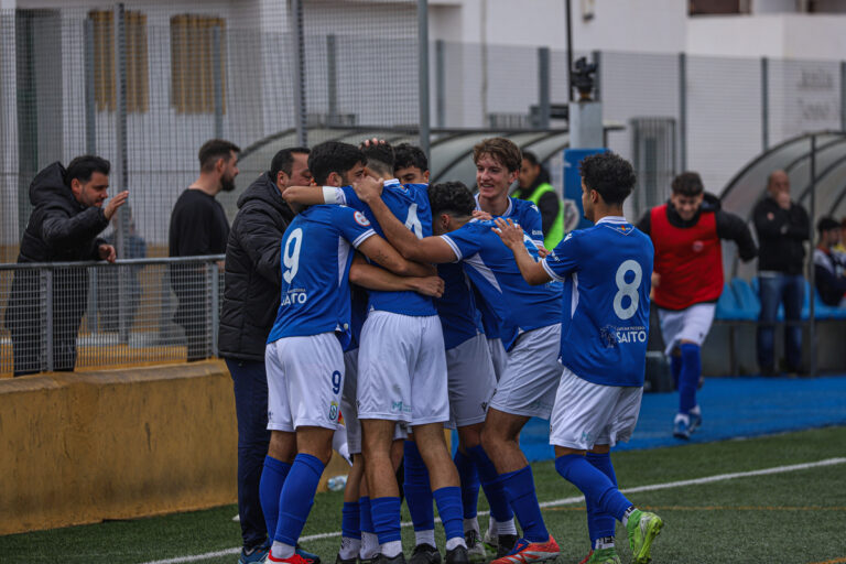 Jugadores de la U.D. Melilla celebrando un gol en el campo.