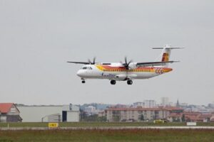 Avión aterrizando en un aeropuerto con edificios al fondo