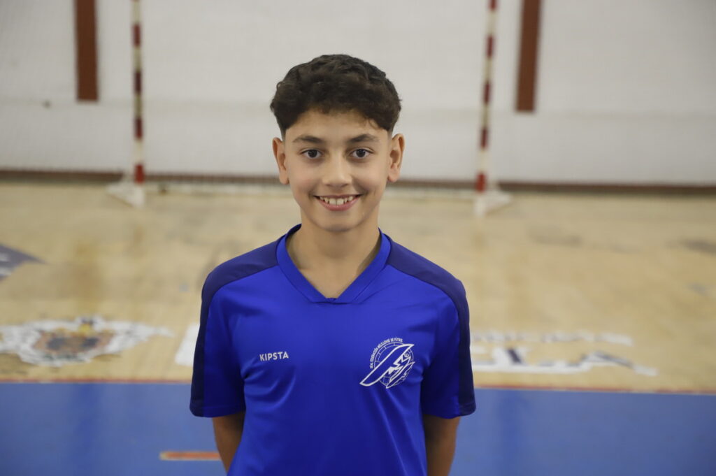 Niño sonriente en uniforme de fútbol sala en un pabellón deportivo