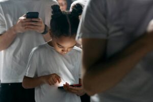 Niña usando un teléfono móvil en un entorno social