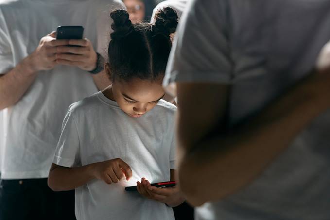Niña usando un teléfono móvil en un entorno social