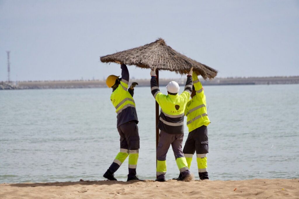 Trabajadores montando sombrillas en la playa de Melilla