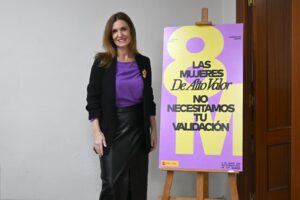 Mujer sonriente junto a un cartel sobre el Día Internacional de las Mujeres