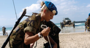 Mujer soldado en la playa con uniforme militar y gorra