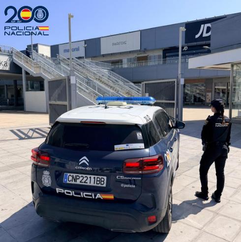 Vehículo de policía en el centro comercial Parque Murias con un agente de pie
