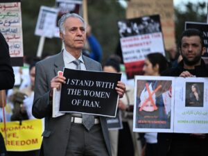 Hombre sosteniendo un cartel en protesta por los derechos de las mujeres en Irán.