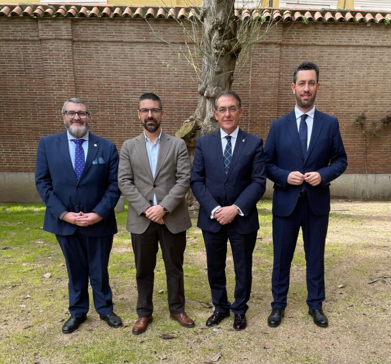 Cuatro hombres de pie en un jardín con un árbol detrás