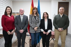 Grupo de personas posando en una oficina con banderas de fondo