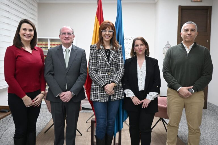 Grupo de personas posando en una oficina con banderas de fondo