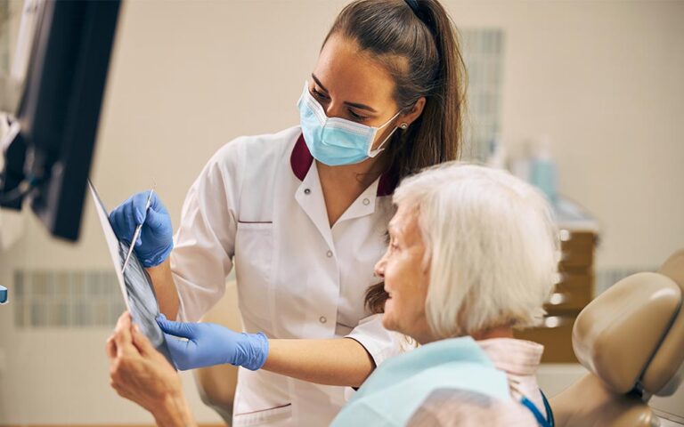 Dentista mostrando radiografía a una paciente mayor en consulta dental