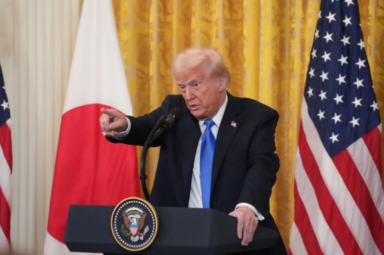 Donald Trump hablando en una conferencia de prensa con banderas de Estados Unidos y Japón