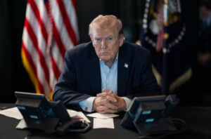 Donald Trump sentado frente a dos teléfonos en una mesa