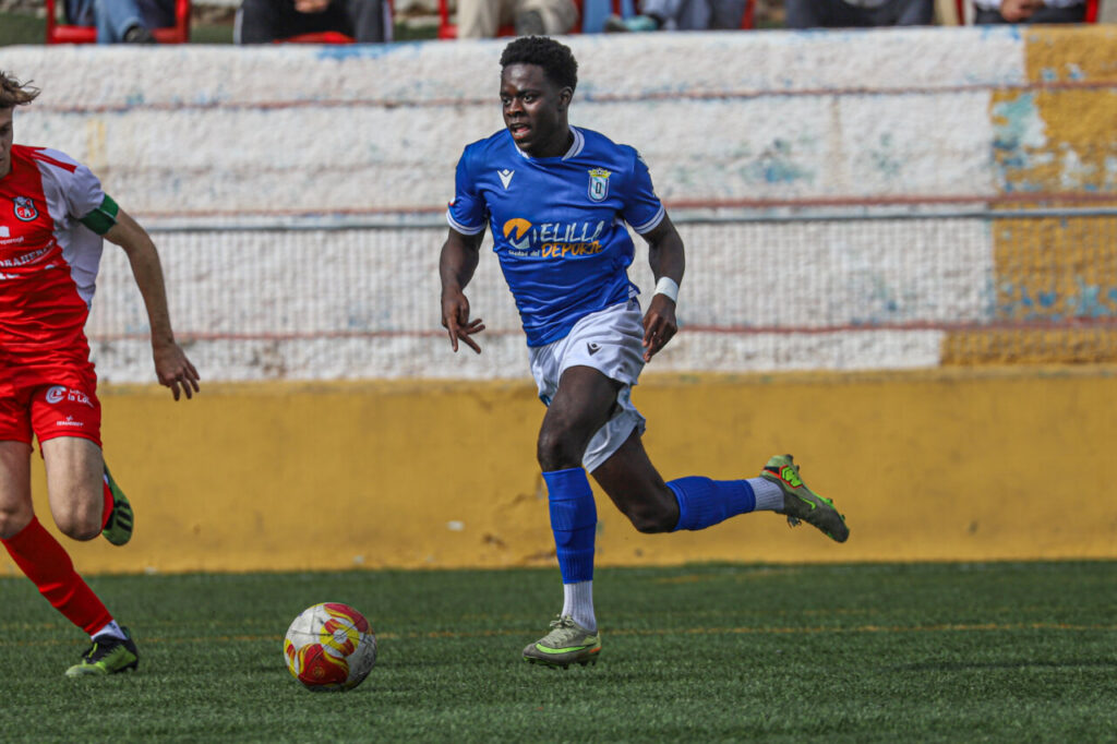 Jugador del filial de la U.D. Melilla corriendo durante un partido de fútbol