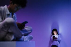 Niños usando teléfonos móviles en un entorno oscuro y colorido