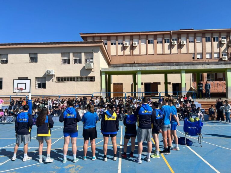 Jugadoras del MCD La Salle interactuando con alumnos en el patio escolar.