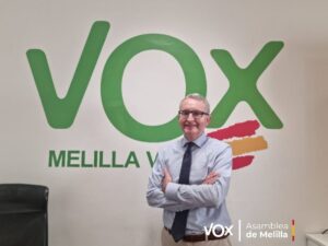Persona posando frente al logo de Vox en Melilla