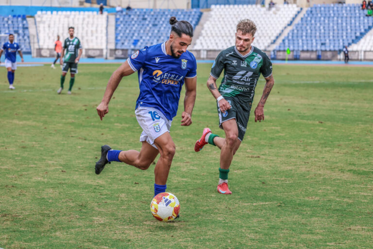 Jugador de la UD Melilla corriendo con el balón en un partido de fútbol