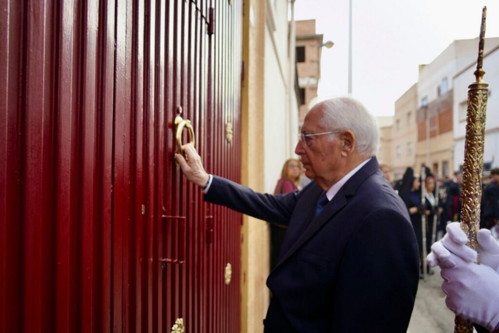 Hombre tocando el aldabón de una puerta en Melilla durante la procesión.