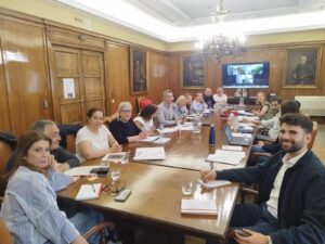 Grupo de personas reunidas en una mesa de trabajo con documentos y laptops.