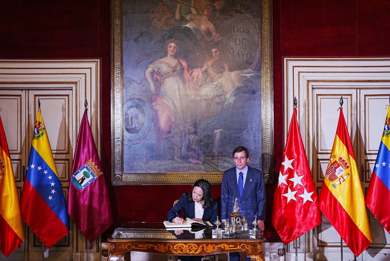 Firma de un acuerdo con banderas de España y Venezuela de fondo