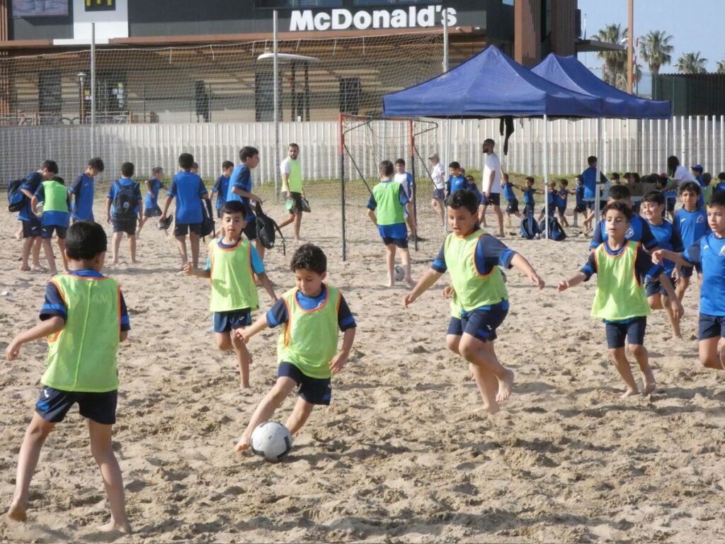 Alumnos de la Escuela de la Fundación RFMF jugando fútbol playa en la arena
