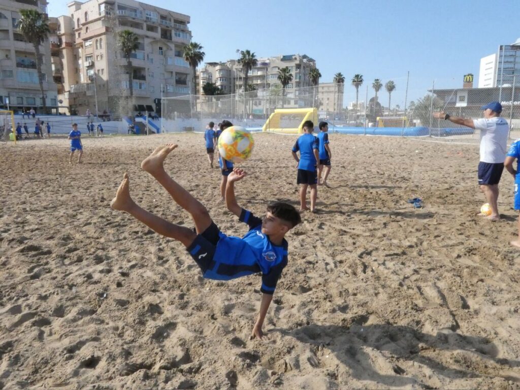 Niños jugando fútbol playa en la playa de San Lorenzo