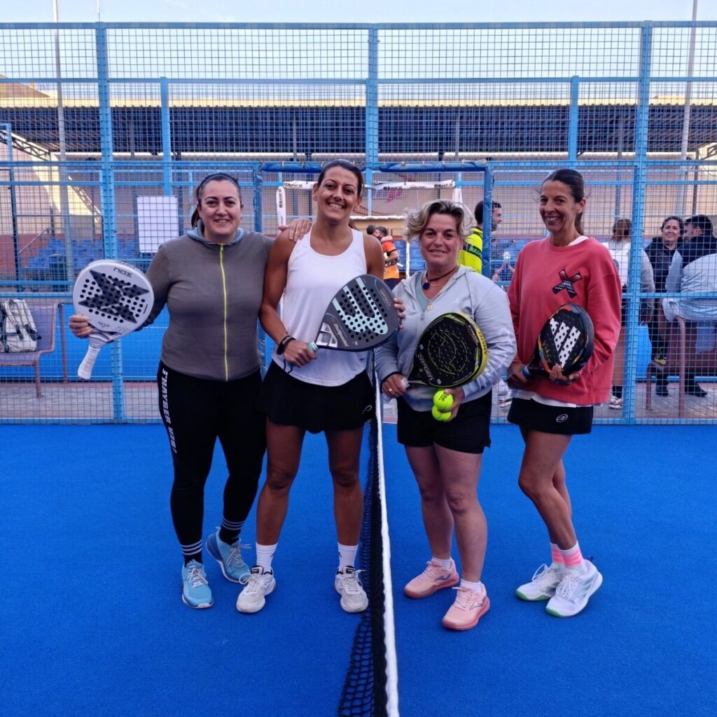 Cuatro jugadoras de pádel posando con sus palas en la cancha
