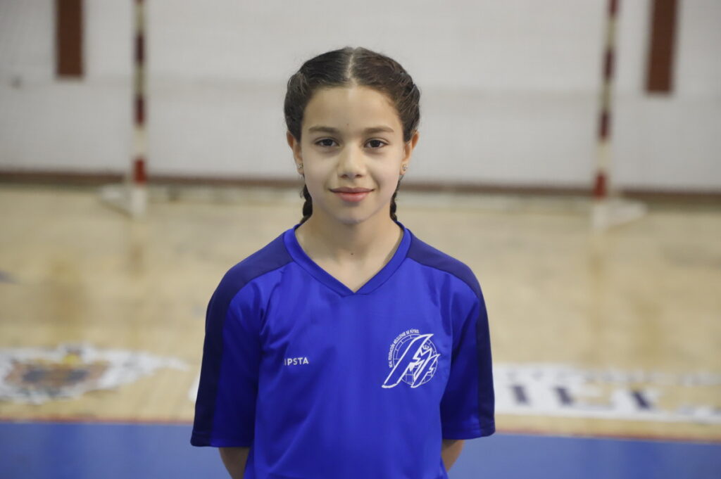 Niña sonriente en camiseta azul en un gimnasio