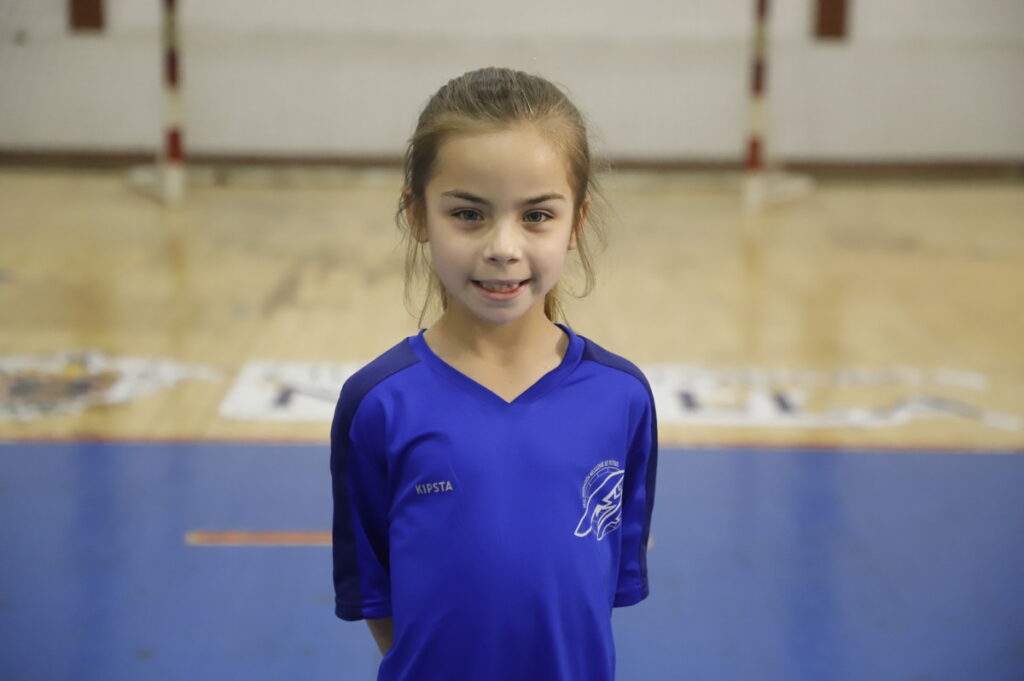 Niña sonriente en camiseta azul en un gimnasio