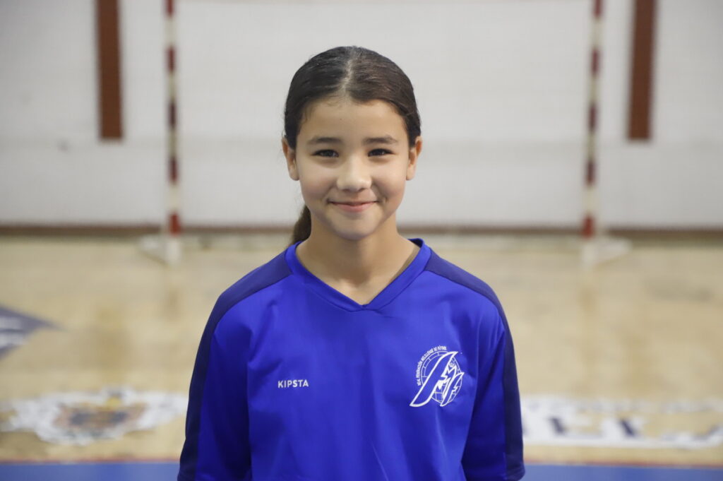 Niña sonriente con camiseta azul en un gimnasio