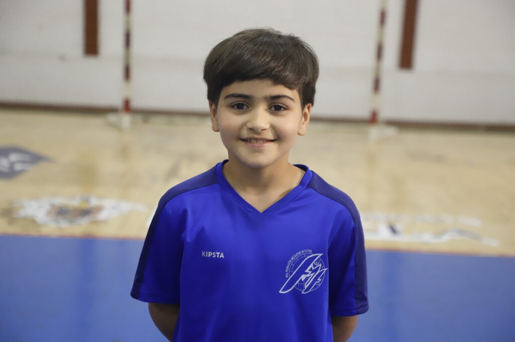 Niño sonriente en camiseta azul en un gimnasio
