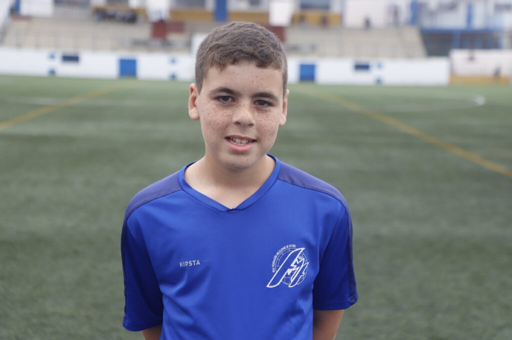 Niño sonriente en uniforme de fútbol en el campo