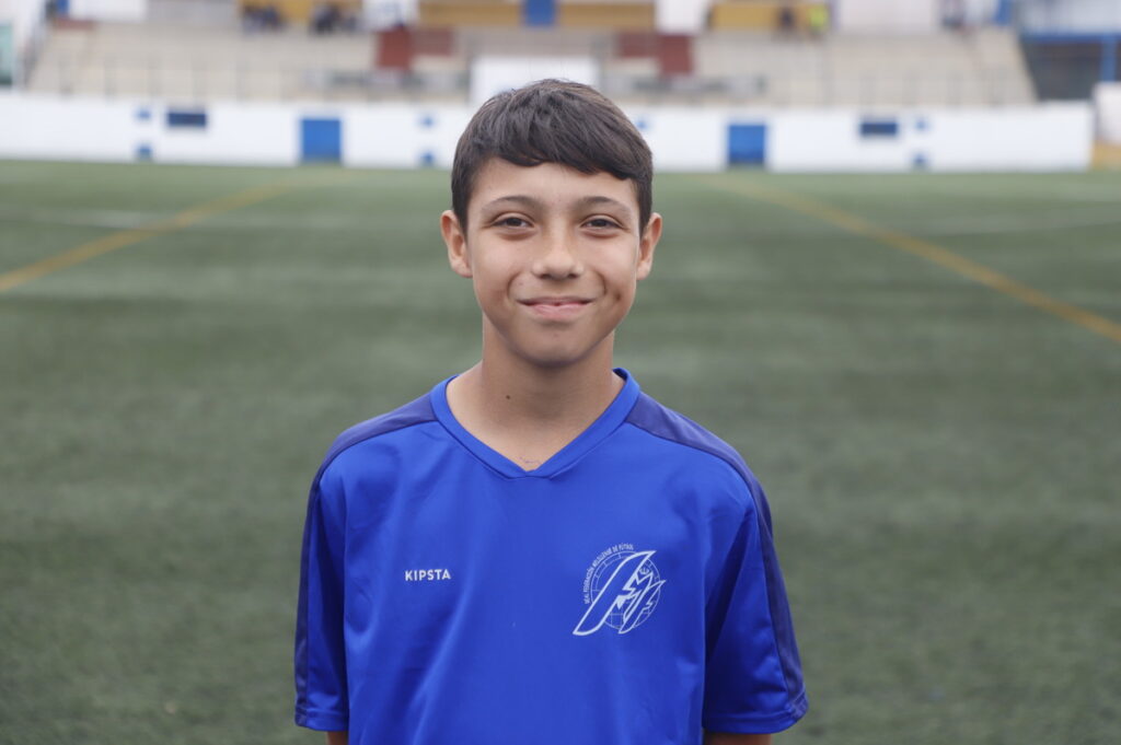 Niño sonriente en uniforme de fútbol en un campo