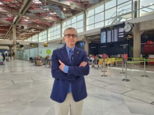 Hombre en un aeropuerto con brazos cruzados esperando su vuelo.