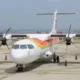 Twin-engine turboprop passenger plane parked on an airport tarmac with traffic cones nearby.