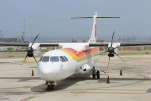 Twin-engine turboprop passenger plane parked on an airport tarmac with traffic cones nearby.