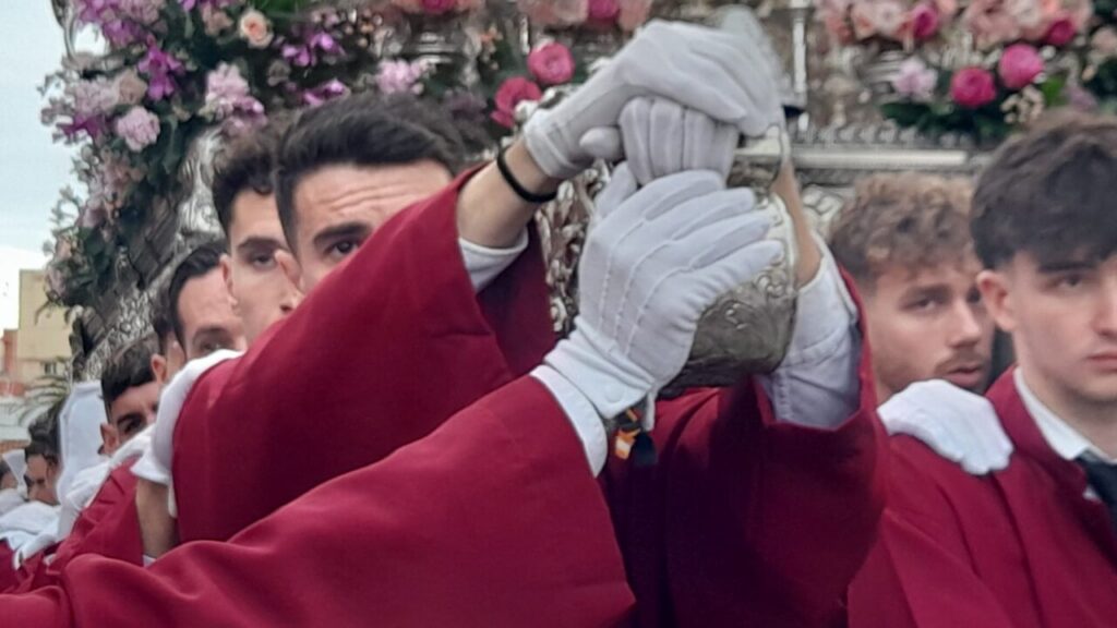 Hombres con túnicas rojas sosteniendo un paso en la procesión de Jueves Santo.