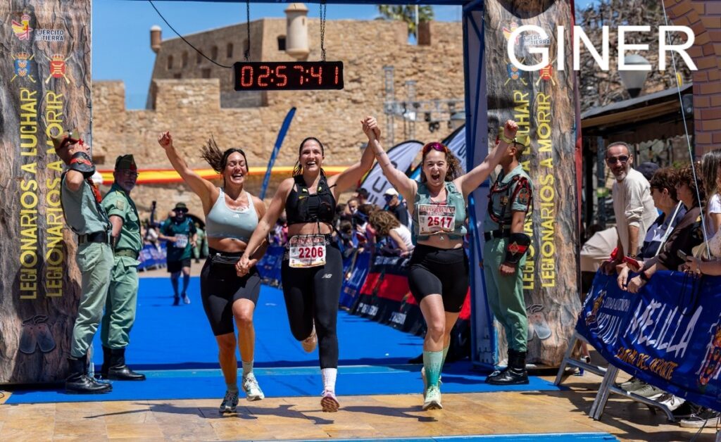 Tres chicas corriendo felices al cruzar la meta en una carrera.