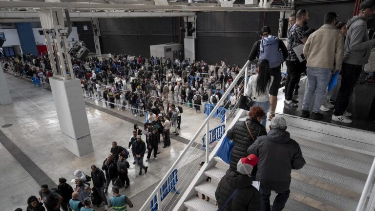 Multitud de personas en una larga cola para trámites administrativos