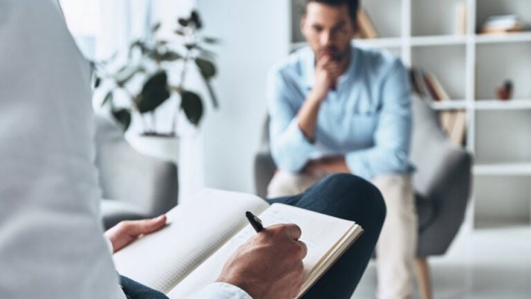 Psicólogo clínico tomando notas durante una sesión con un paciente