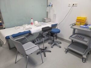 Consultorio médico con mesa, sillas y equipo de salud.