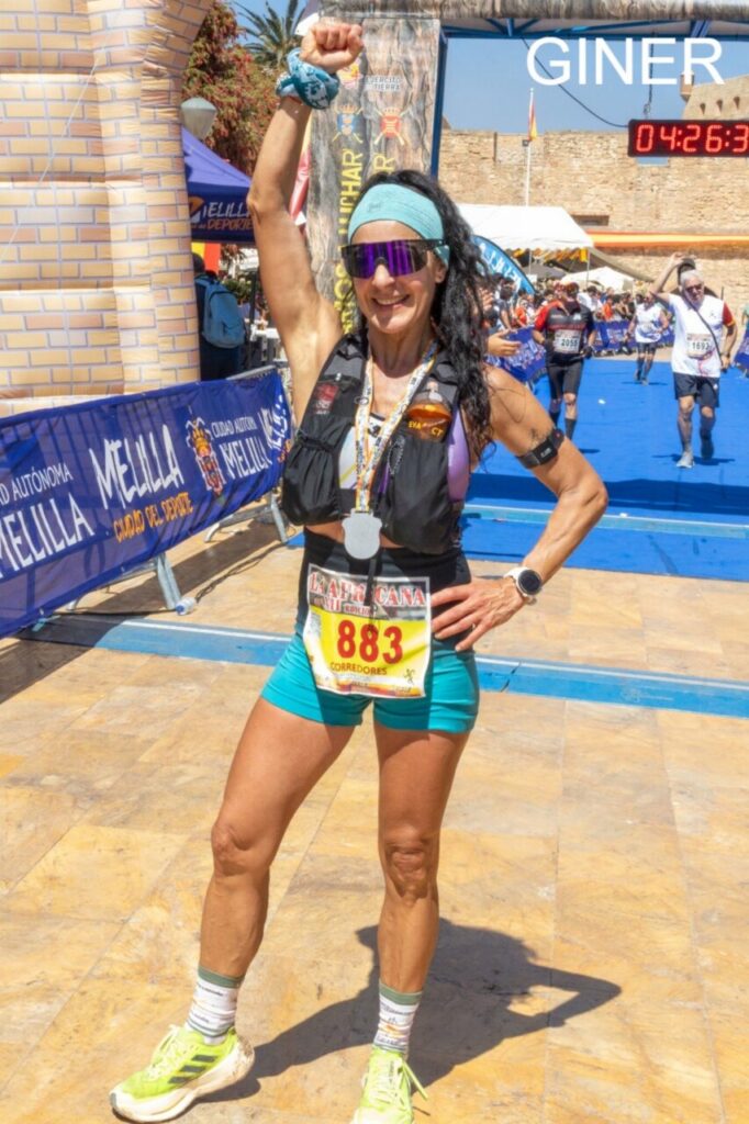 Corredora levantando el puño con medalla en la carrera de Melilla