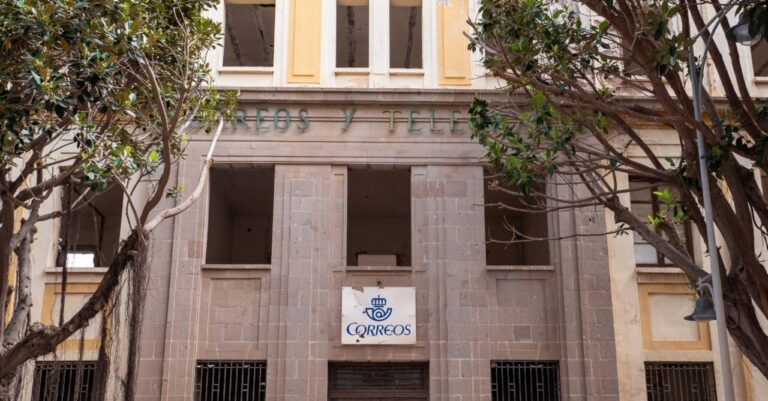 Fachada del antiguo edificio de Correos en Melilla con árboles alrededor.