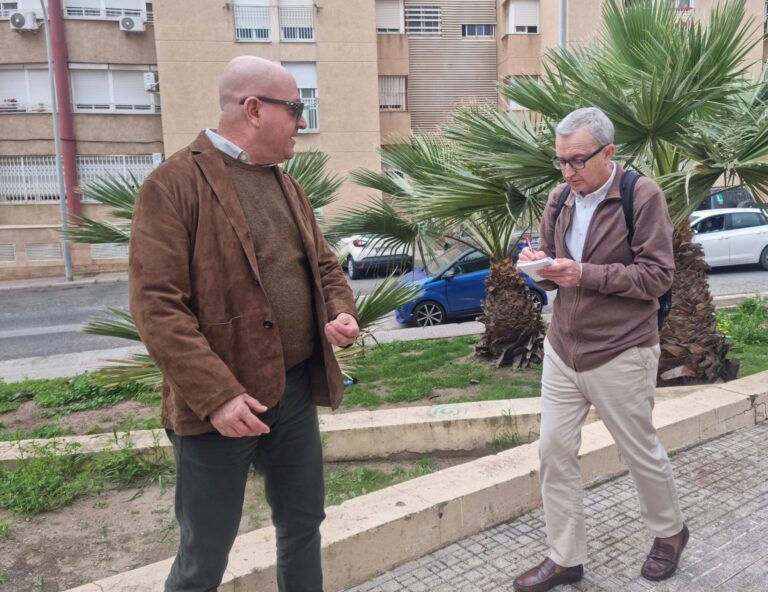 Dos hombres conversando en la calle junto a palmeras