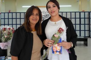 Dos mujeres sonrientes sosteniendo flores en un evento