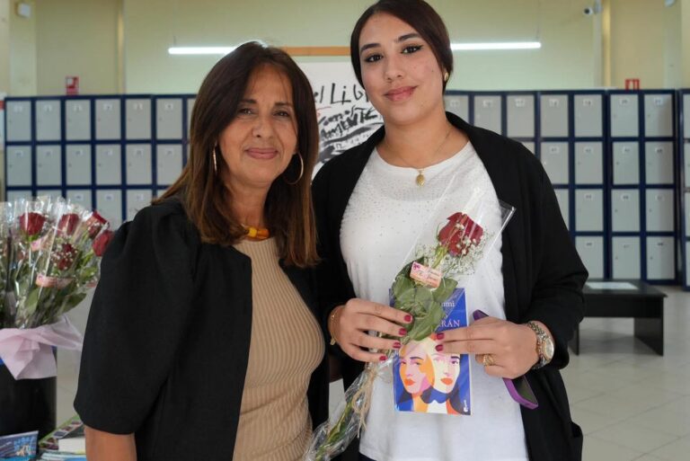 Dos mujeres sonrientes sosteniendo flores en un evento