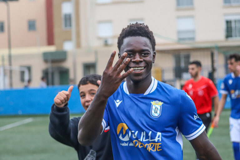 Jugador de fútbol sonriente mostrando cuatro goles en un partido