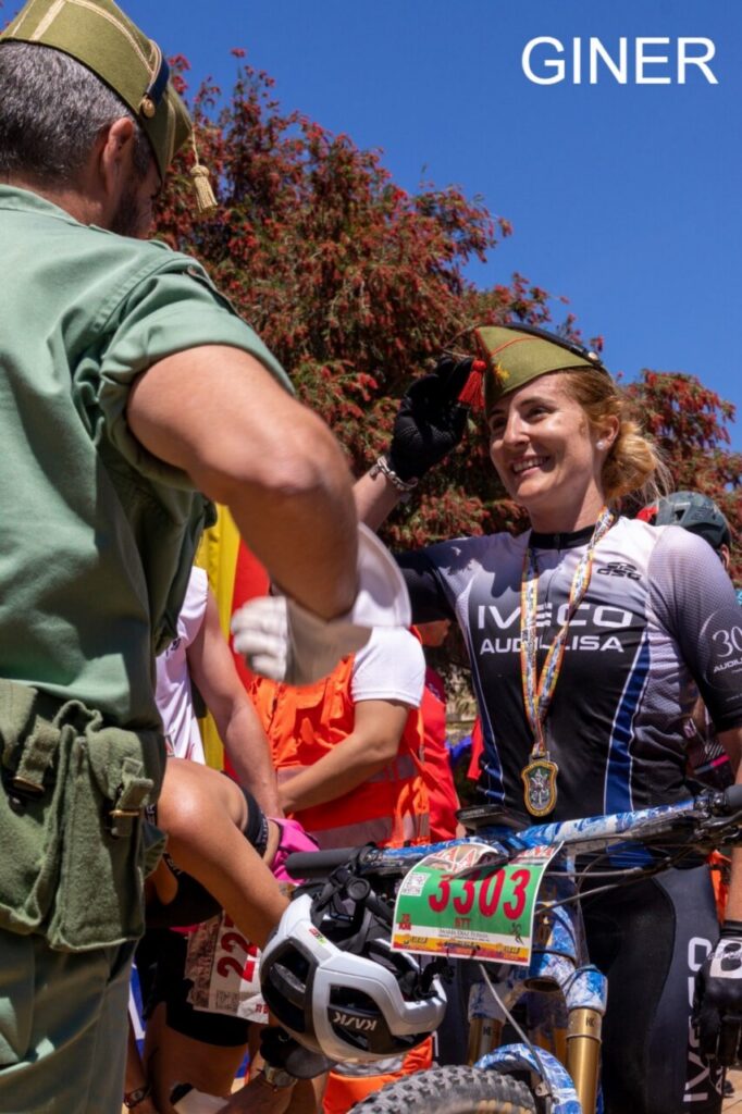 Mujer saludando en una competencia de ciclismo con medalla