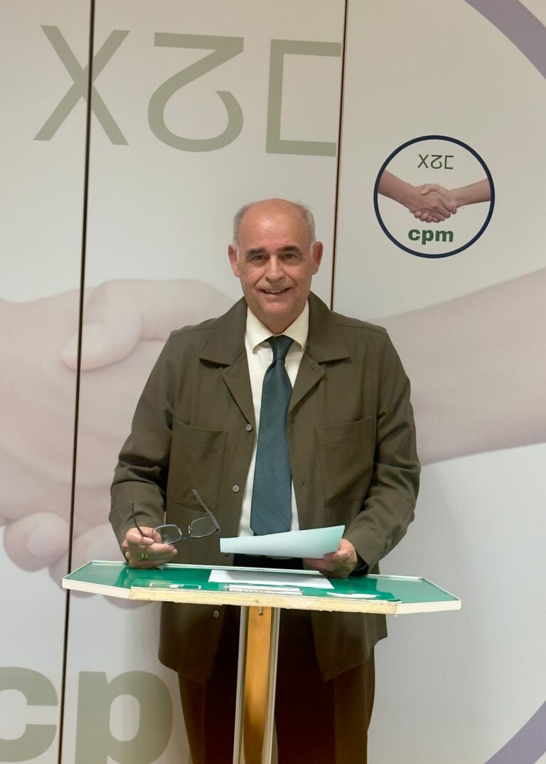 Hombre sosteniendo documentos en un evento con fondo de manos estrechándose