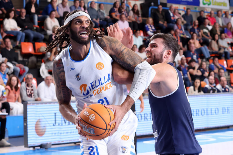 Dos jugadores de baloncesto compiten por el balón en la cancha.